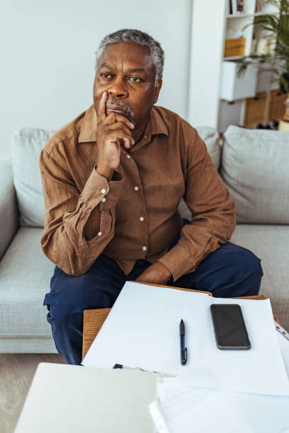 istock Senior man looking out of window at home 1412853552