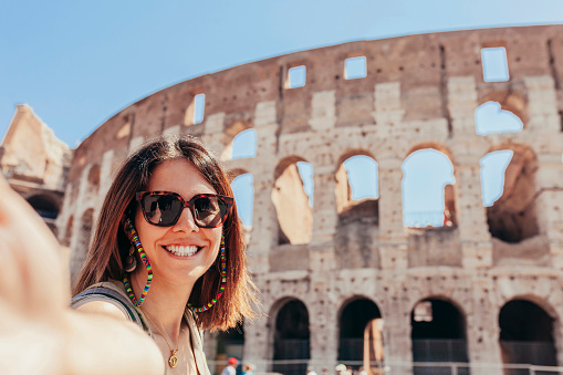Young cheerful caucasian woman taking selfie, in front of Colosseum, Rome, Italy. Holiday, travel, vacation, tourist, summer concept.