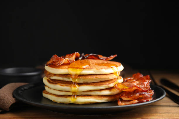 istock Delicious pancakes with maple syrup and fried bacon on wooden table 1412854451