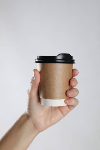 istock Woman holding takeaway paper coffee cup on white background, closeup 1412854564