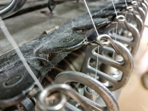 horizontal view of an outdoors shop of wools dyed with natural dyes and an antique pedal wooden spinning wheel in the foreground