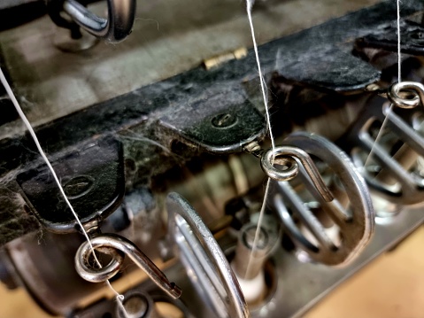 Close-up of a cotton spinning machine. The detail shows how the thin cotton thread comes out of the machine. Captured on a collection of old cotton prcessing machines.
