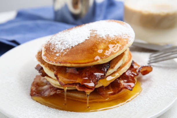 istock Delicious pancakes with maple syrup, sugar powder and fried bacon on plate, closeup 1412856071