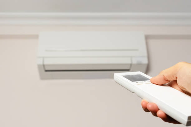 istock Man's hand with remote control turning on the air conditioner. 1412856252