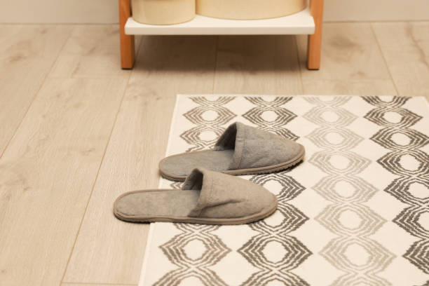 istock Stylish bath mat with soft slippers on floor indoors 1412857315
