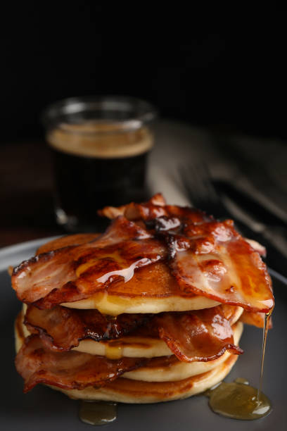 istock Delicious pancakes with maple syrup and fried bacon on plate, closeup 1412857543