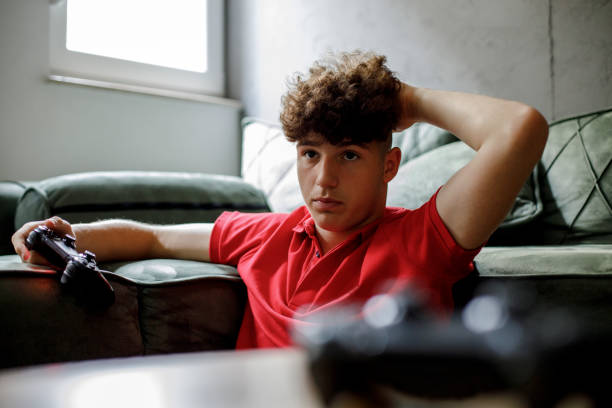 A young male teenager is playing video games on his playstation and is worked up about his score.
