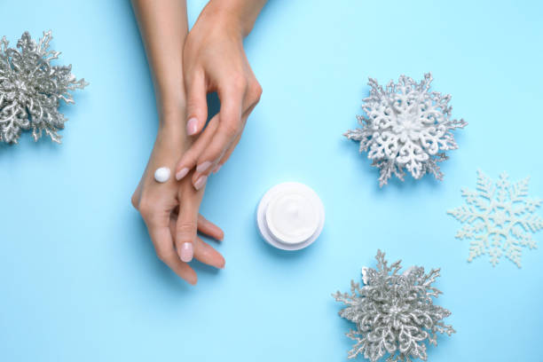 istock Woman applying cream onto hand on light blue background, top view 1412857722