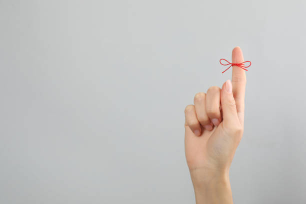 woman showing index finger with tied red bow as reminder on light grey background, closeup. space for text - forget me not imagens e fotografias de stock