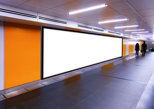 Long horizontal long mock up of blank advertising billboard poster template in a long tunnel walkway; out-of-home OOH media display advertisement mockup in pedestrian underpass; digital display