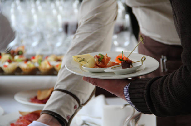 mano de hombre con un plato de aperitivos en la mesa de catering - canape buffet cocktail food fotografías e imágenes de stock