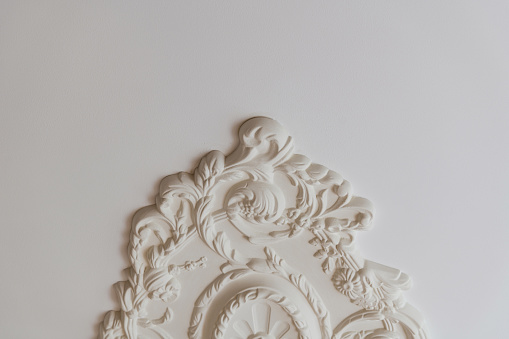 Vintage Stucco elements on light luxury wall. White patterned. Moulding element from gypsum. Close up shot. High quality photo.