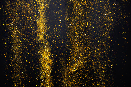 Falling rain of gold glitter particles lights abstract bokeh dark background