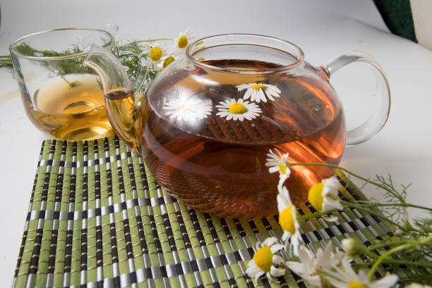 istock Chamomile tea stands in a transparent bowl on a green stand on a light background 1412863658