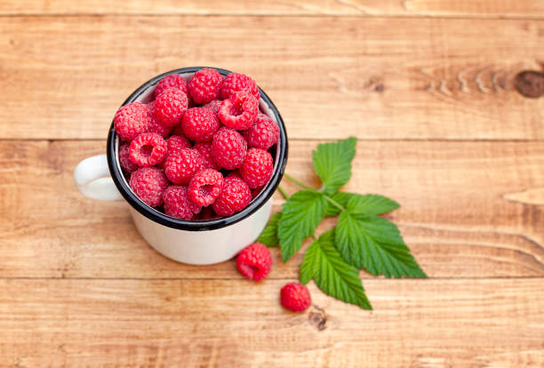 mug with raspberries close-up on a wooden table - raspberry table wood autumn imagens e fotografias de stock