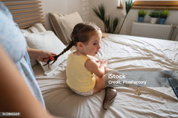 Unrecognizable Mother Making Pigtails To Her Toddler Daughter Stock Photo - Download Image Now