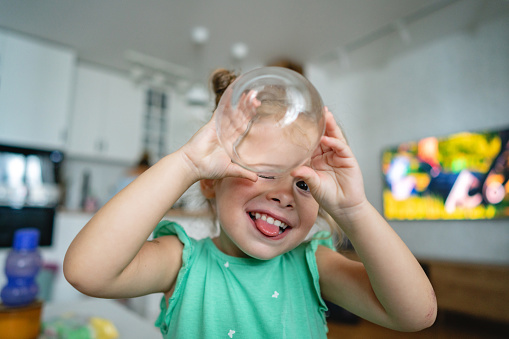 Portrait of cute Caucasian toddler girl playing with a drinking glass
