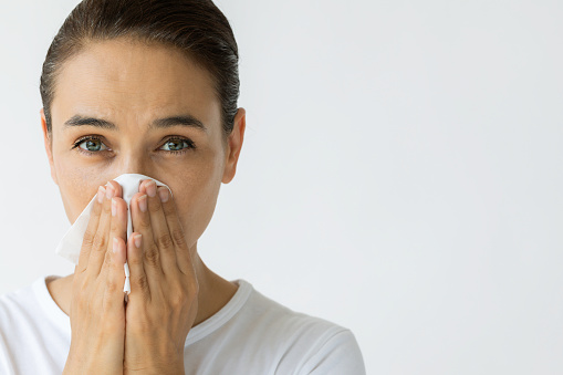 Caucasian female is cleaning nose with tissue.