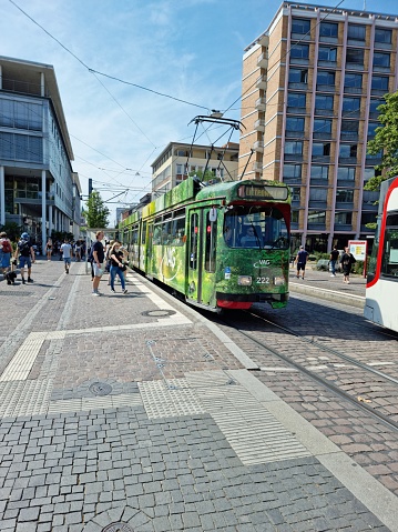 Freiburg im Breisgau city life with a tram (cable car) and some pedestrians in the modern city. The image was captured during summer season.