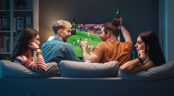 istock Girls talking while men are watching soccer on TV 1412870466