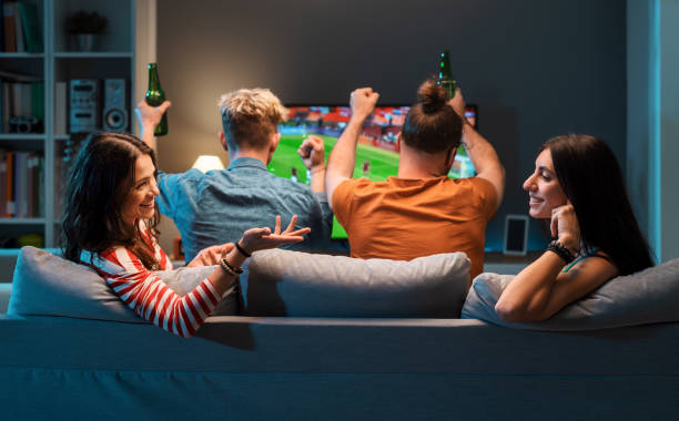 istock Girls talking while men are watching soccer on TV 1412870960