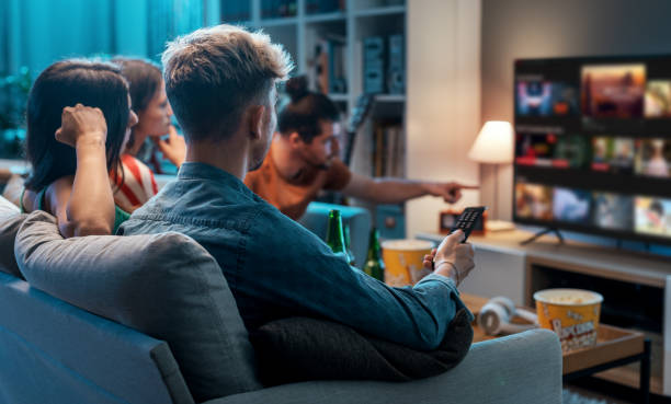 Friends watching movies together at home Friends choosing a movie to watch together at home, video on demand concept television set stock pictures, royalty-free photos & images