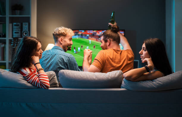 istock Girls talking while men are watching soccer on TV 1412871777