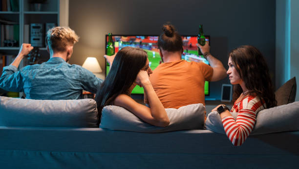 istock Girls talking while men are watching soccer on TV 1412871819