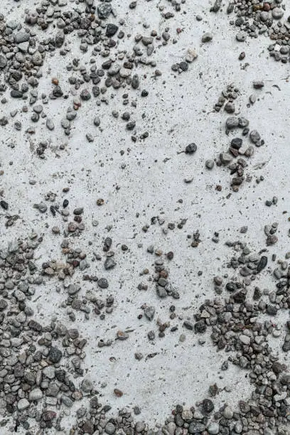 close-up of small gray stones scattered on light stone surface. Vertical view. Stone texture. Wallpaper template. Abstract background texture