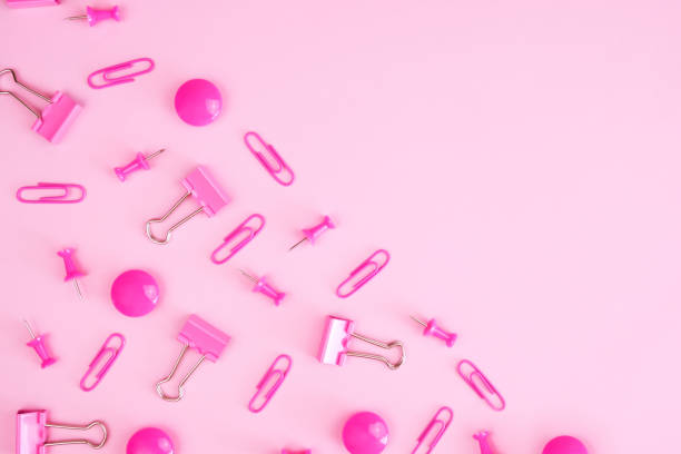 istock Pink blank divided diagonally. Scattered on the half paper clips, push pins, binder clips 1412874519
