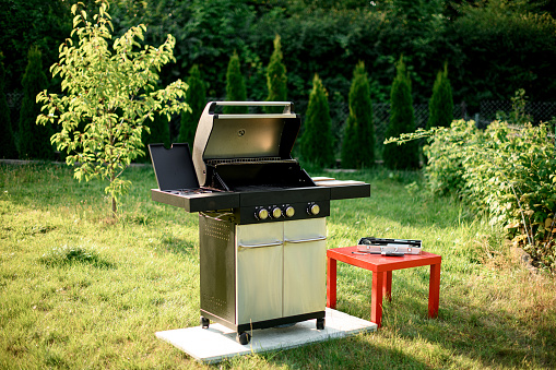 Great view on modern stainless portable BBQ barbecue grill at yard. Outdoor major kitchen appliances