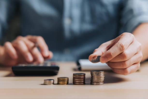 geschäftsmann, der münzen hält, die mit dem taschenrechner in glas gesteckt werden, um das konzept zu berechnen und geld für die finanzbuchhaltung zu sparen - zählen stock-fotos und bilder