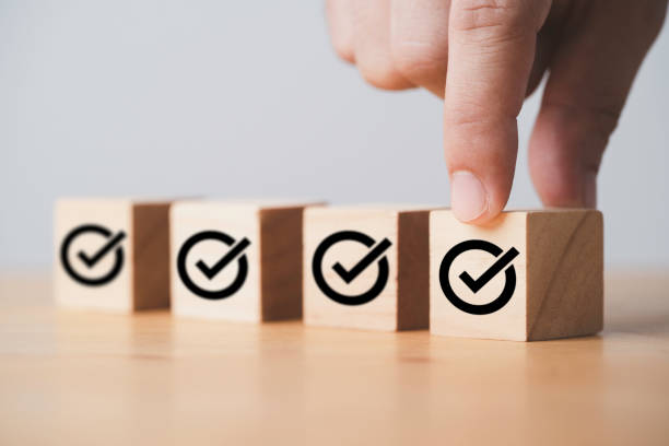 istock Hand putting correct sign which print screen on wooden cube block for approve project and ISO document concept. 1412879935