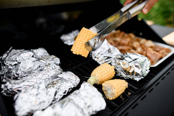 selective focus on freshness corn in tongs over grill grid stock photo