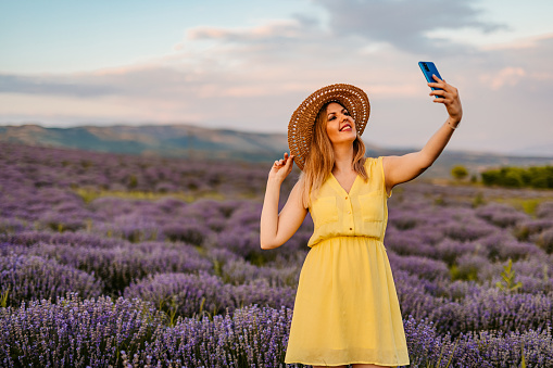 Young beautiful woman taking a selfie in lavender field.