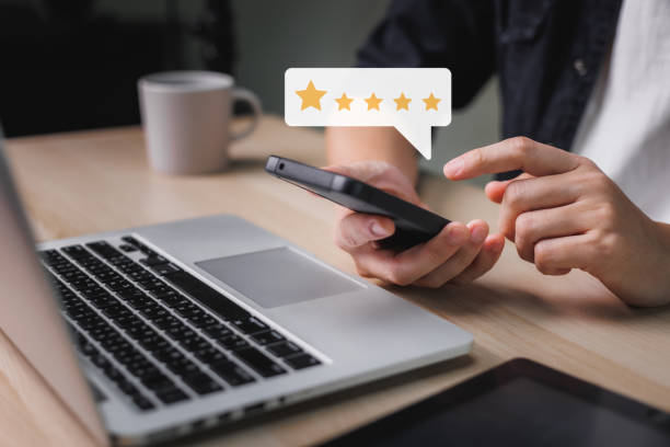 istock Man hand using smartphone with popup five star icon for feedback review satisfaction service at the working on table, Customer service experience, and business satisfaction survey. 1412881582