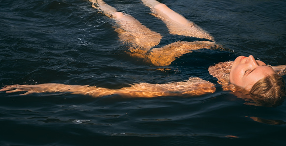 young woman lies in the lake on her back