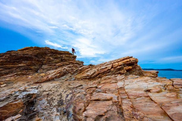 A man is walking on top of a mountain and the sky is colorful at sunset.