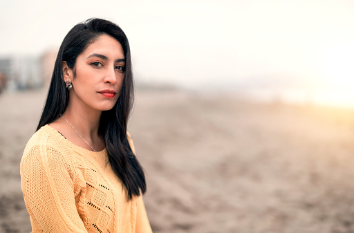 portrait of a young latin woman on the beach looking at the camera with confidence