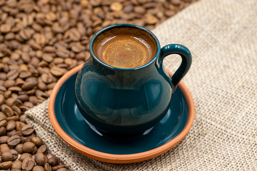 Turkish coffee on wood floor. Rustic turkish coffee cup on cloth. coffee beans in the background