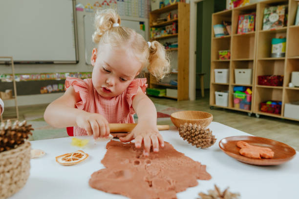 istock Preschool girl making prints on the dough using natural materials 1412887891