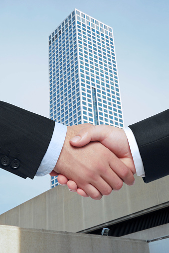 businessmen handshaking in front of a skyscraper