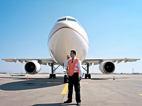 Security guard standing in front of a plane in an airport