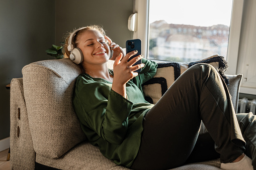 Young woman listening music and using smart phone while relaxing