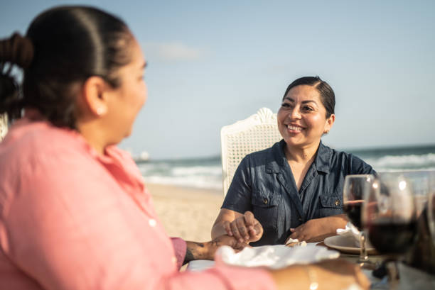 istock Lesbian couple talking and drinking a wine at a beach 1412891759
