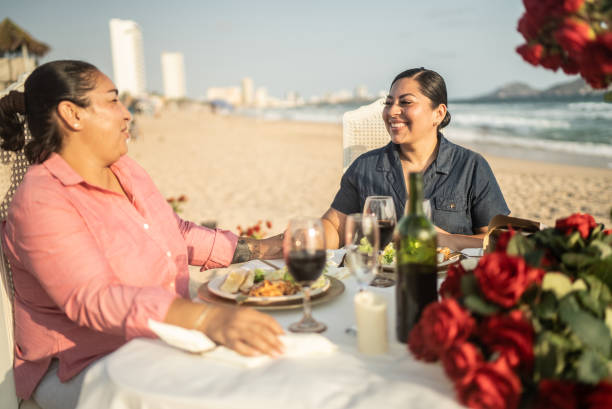 istock Lesbian couple talking and eating at a beach 1412891781