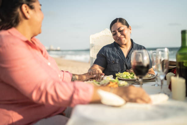 istock Lesbian couple talking and eating at a beach 1412891813
