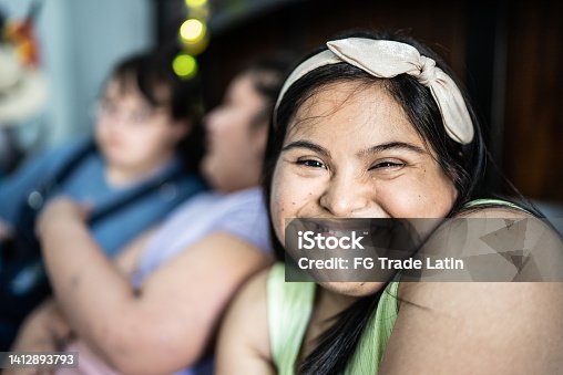 istock Portrait of special needs young woman lying down with friends in the bedroom at house 1412893793