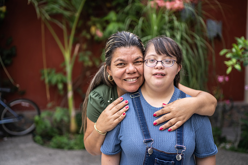 Portrait of mother embracing her daughter with special needs outdoors