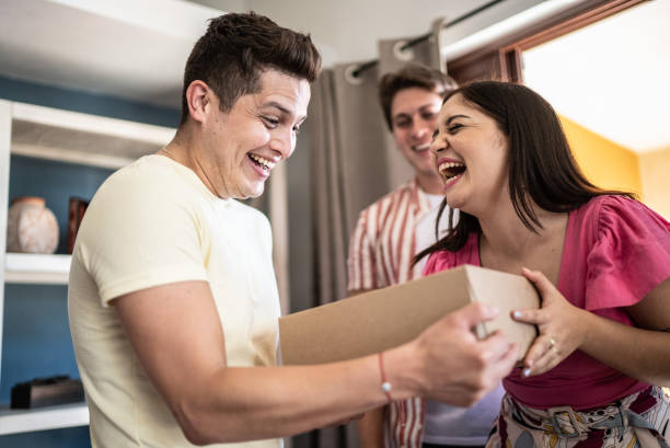 Young man receiving gift from friends at home